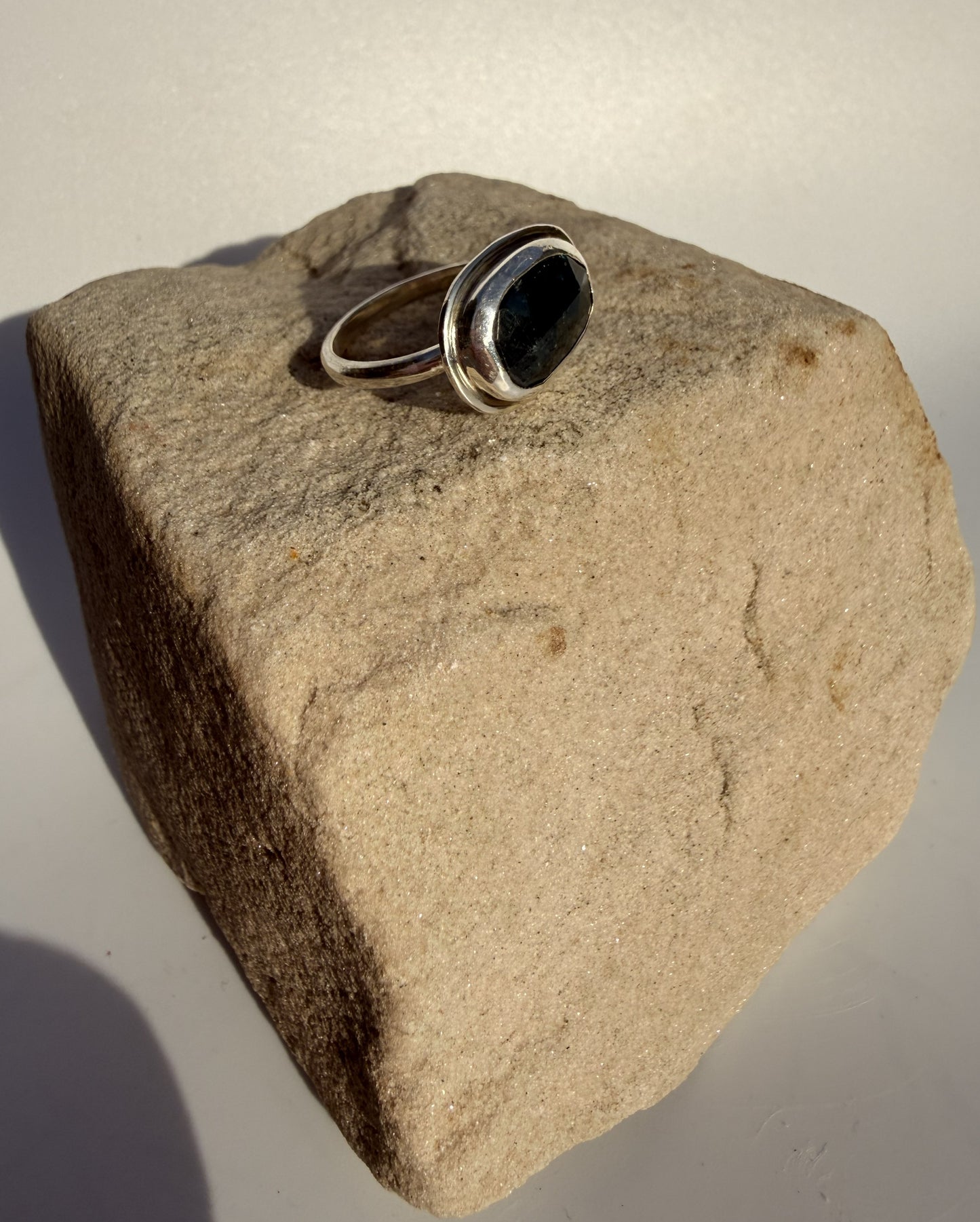 Silver ring with kyanite stone on a textured beige rock
