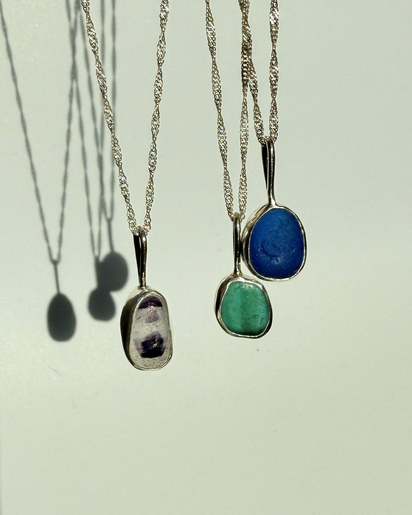 Three necklaces with sea glass on a light background