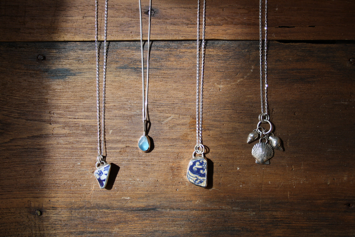 Four necklaces with pendants on a wooden surface