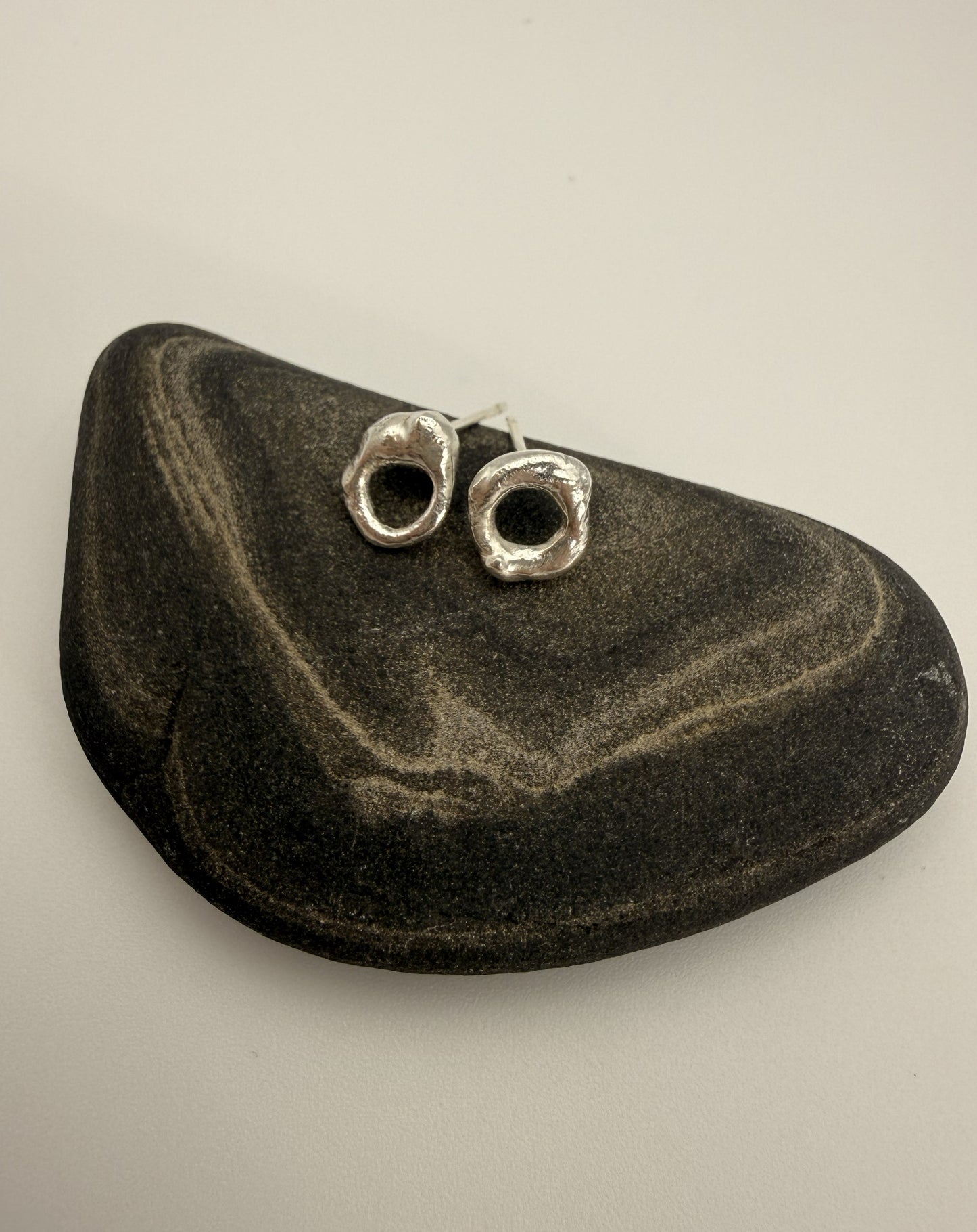 Silver earrings on a black stone against a beige background