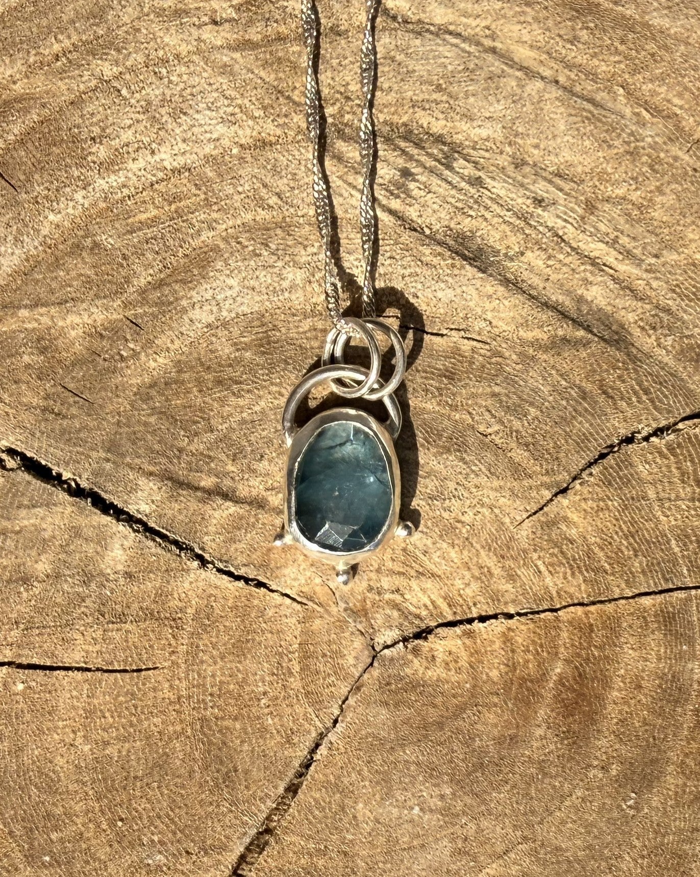 Necklace with a blue kyanite
pendant on a wooden surface