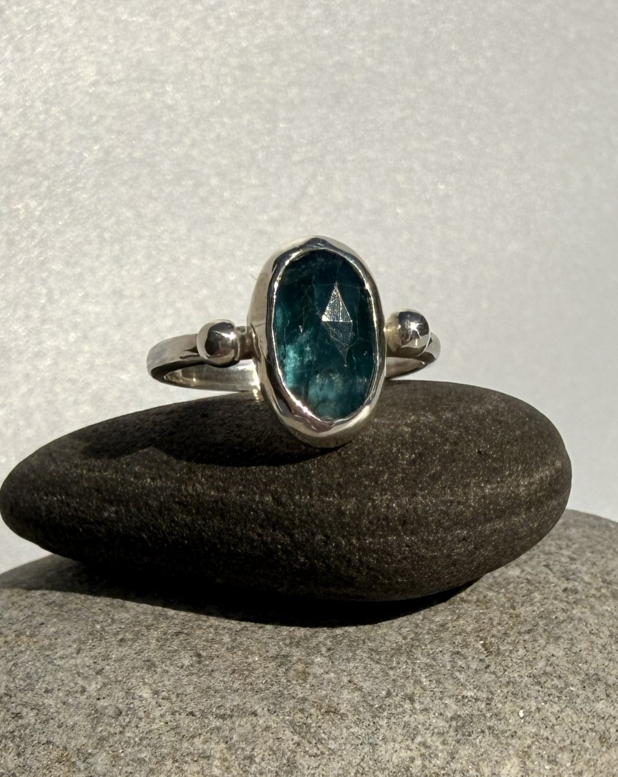 Silver ring with a blue kyanite gemstone on a dark stone surface