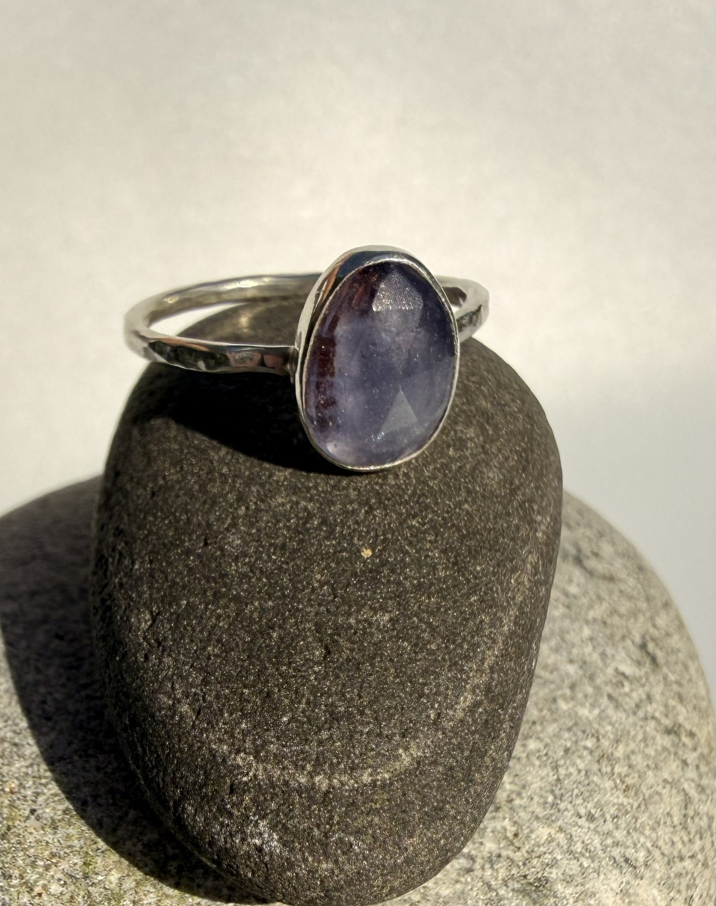 Silver ring with a purple tanzanite stone on a grey rock