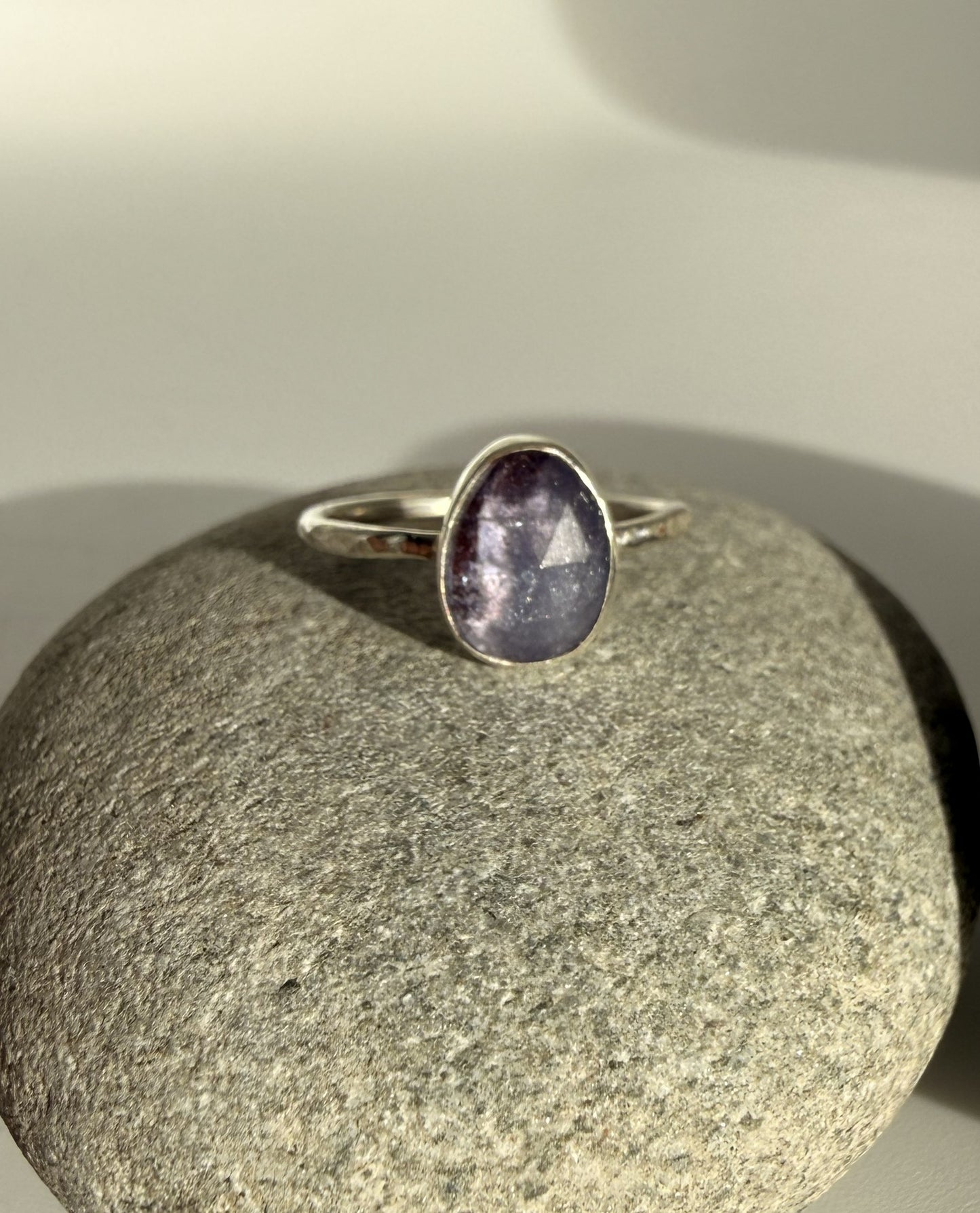 Silver ring with a purple tanzanite stone on a gray stone surface