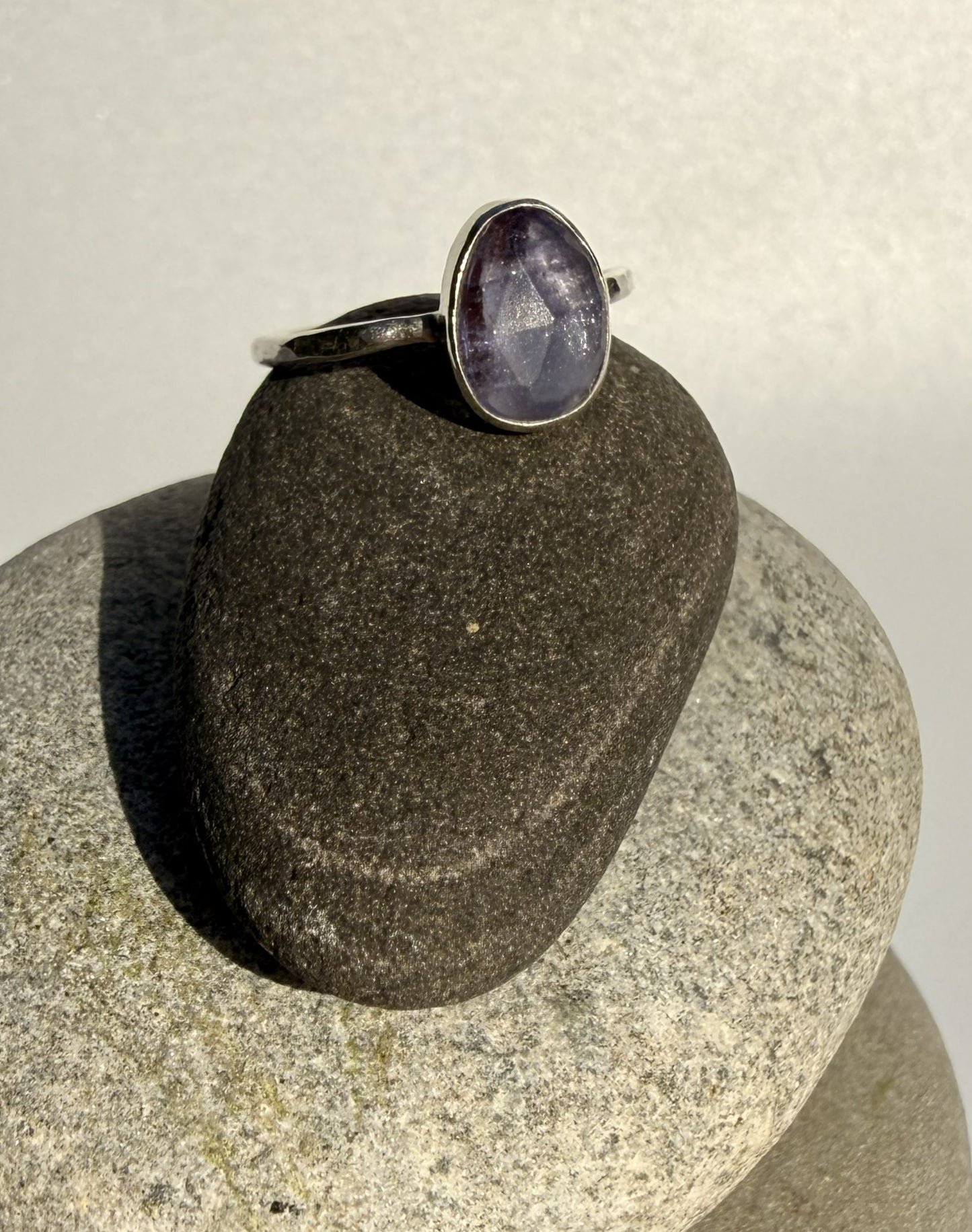 Silver ring with a purple tanzanite stone on a stack of stones