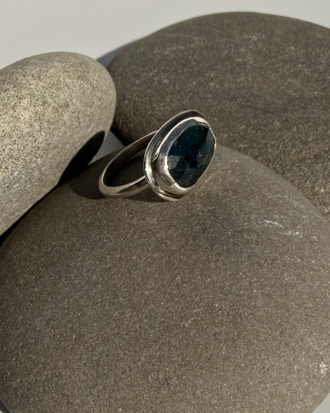 Silver ring with a teal kyanite stone on a grey stone surface