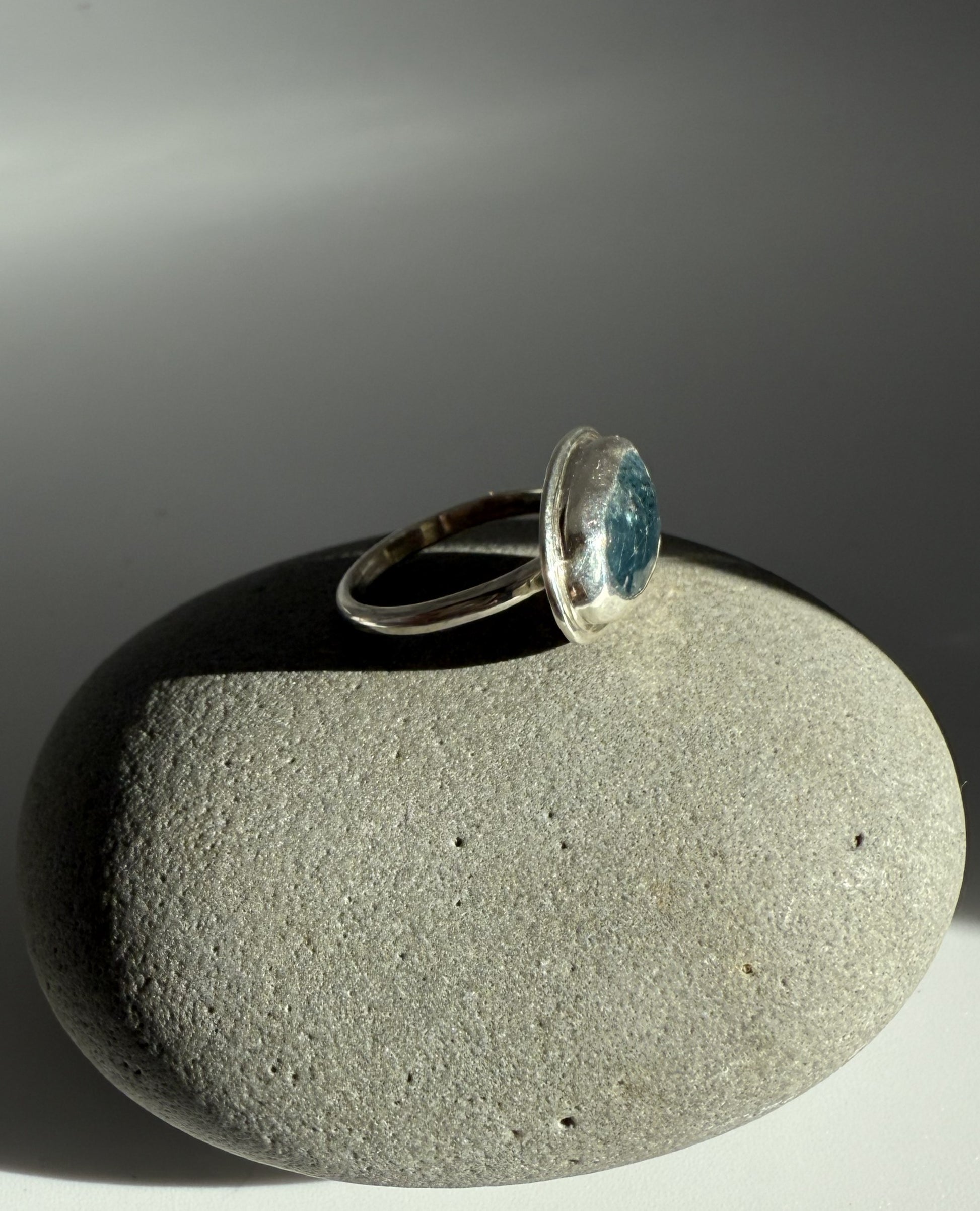 Silver ring with a blue kyanite stone on a gray stone surface