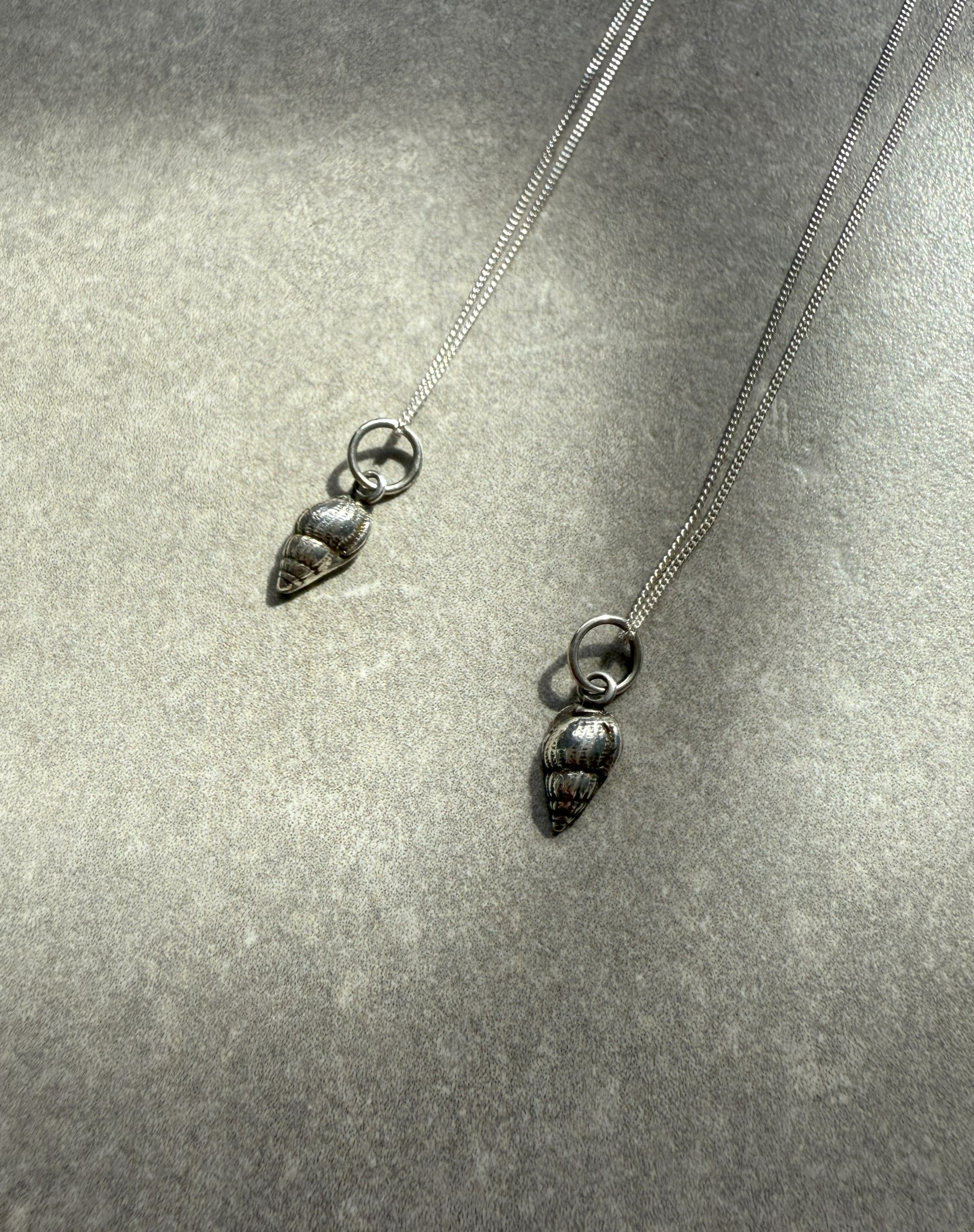 Silver necklace with shell-shaped pendants on a grey background