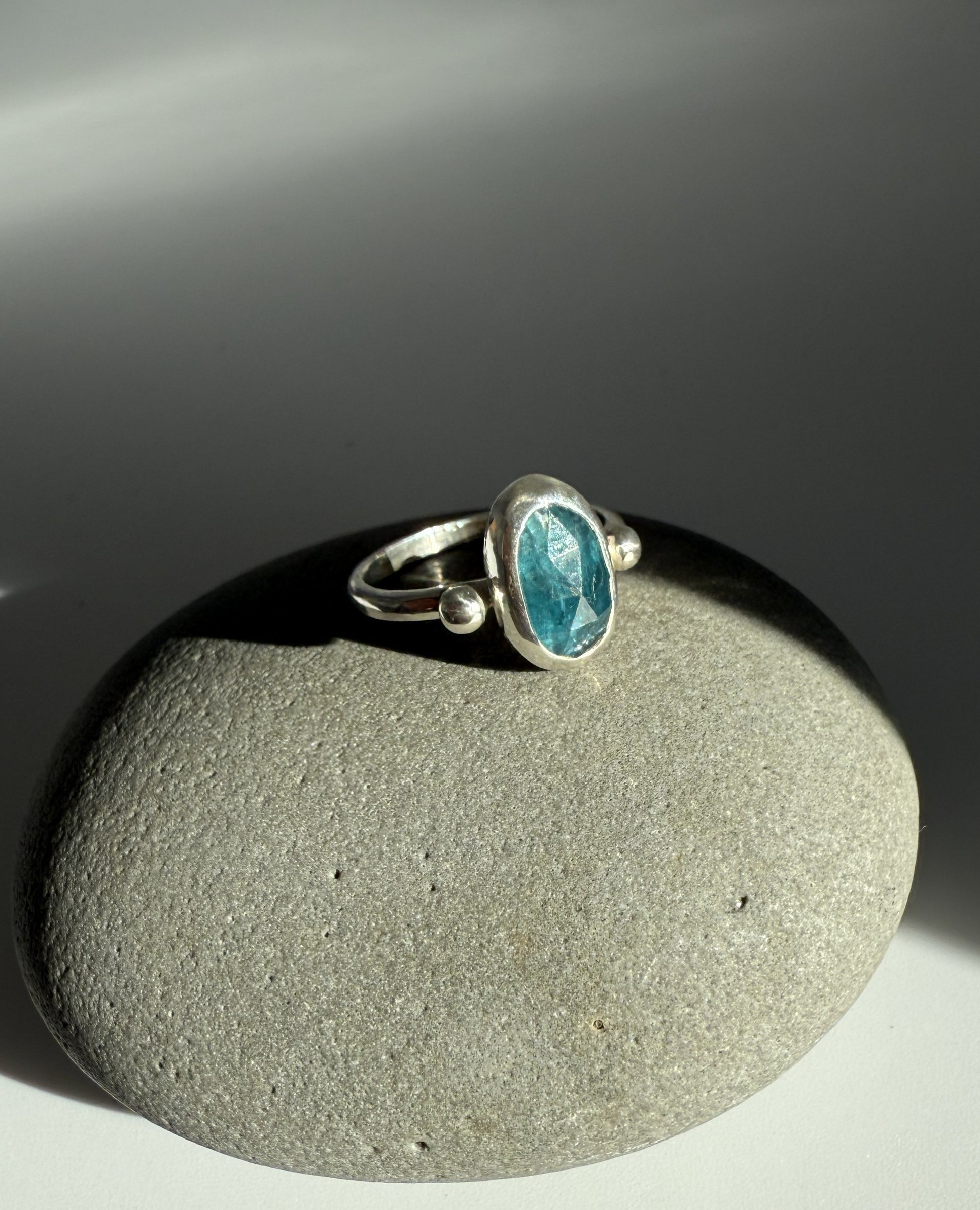 Silver ring with a blue kyanite gemstone on a grey surface