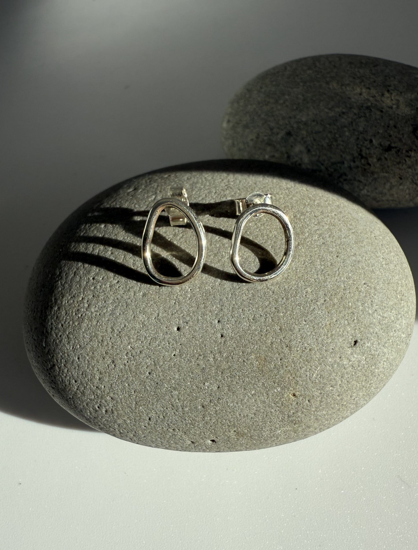 Silver stud earrings on a grey stone surface