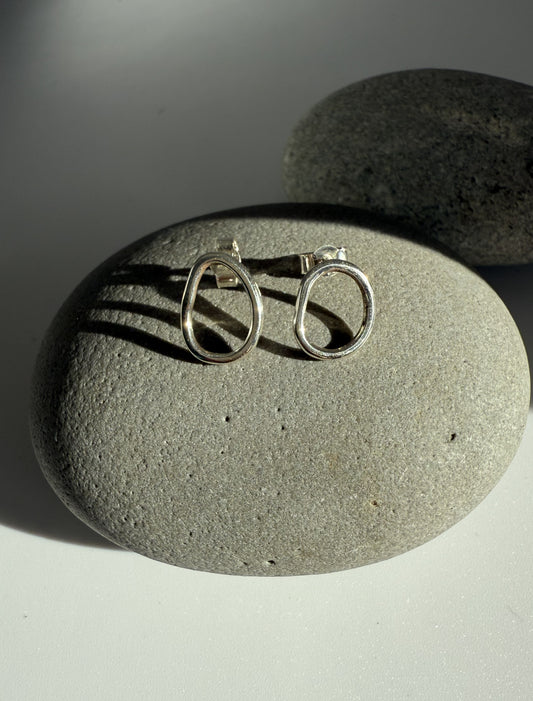 Silver stud earrings on a grey stone surface