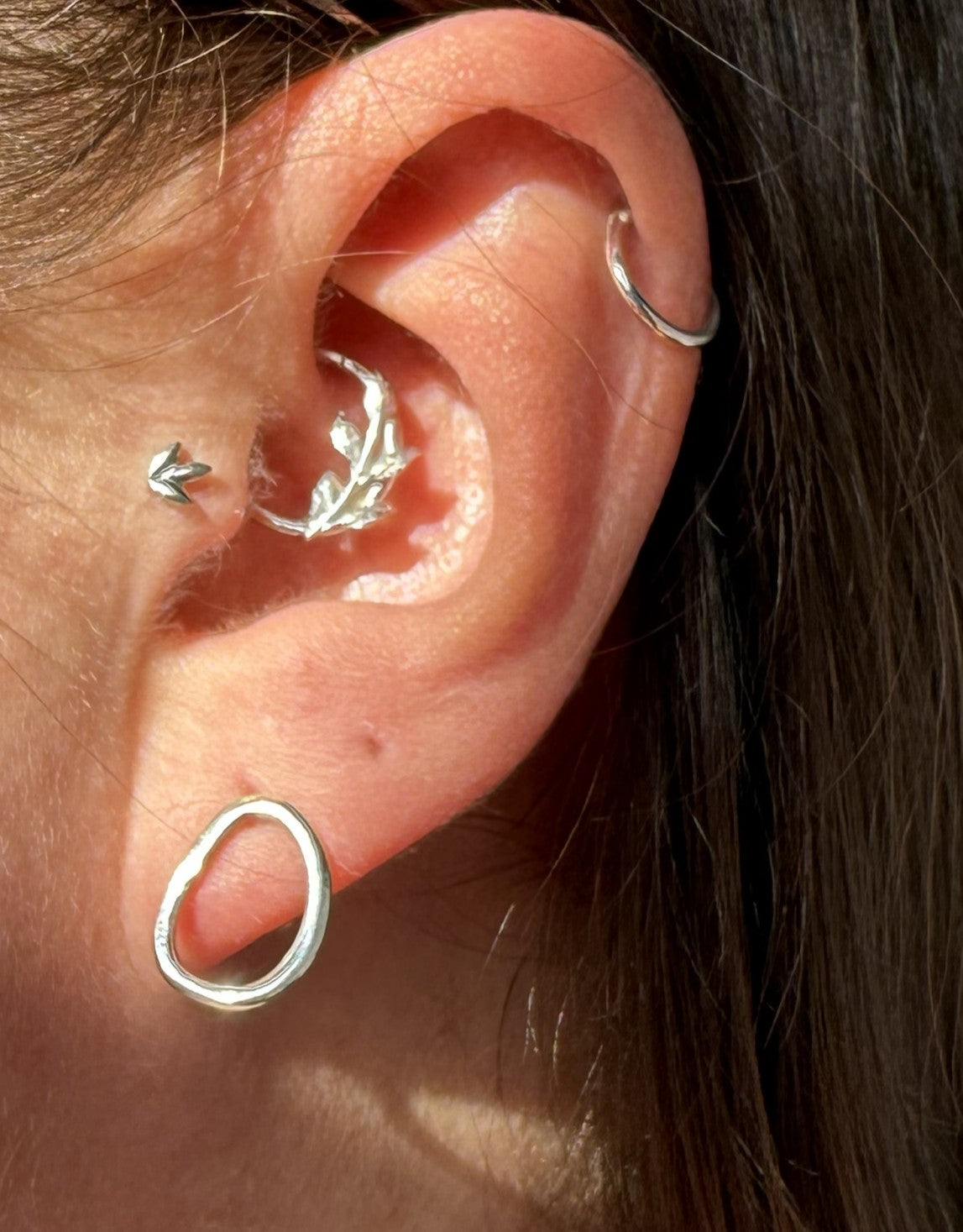 Close-up of an ear with multiple silver earrings