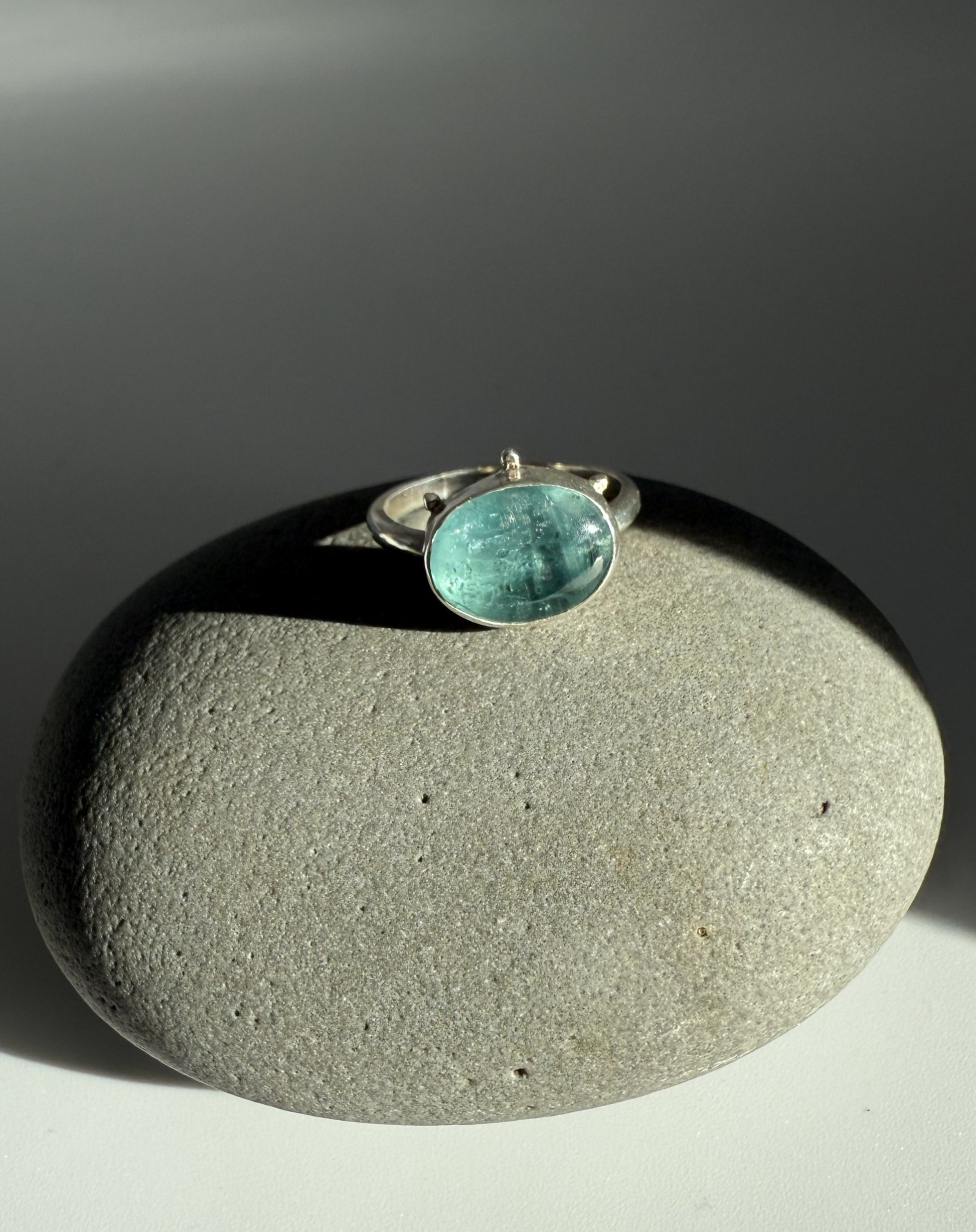 Ring with a turquoise kyanite stone on a grey stone surface