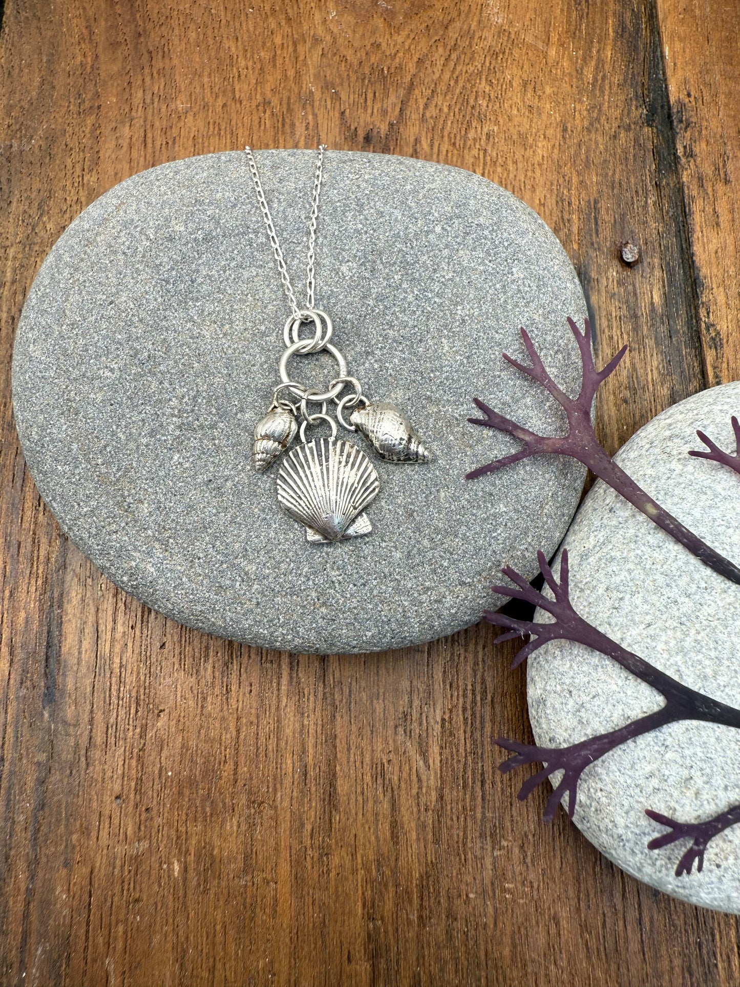 Silver necklace with shell charms on a stone surface