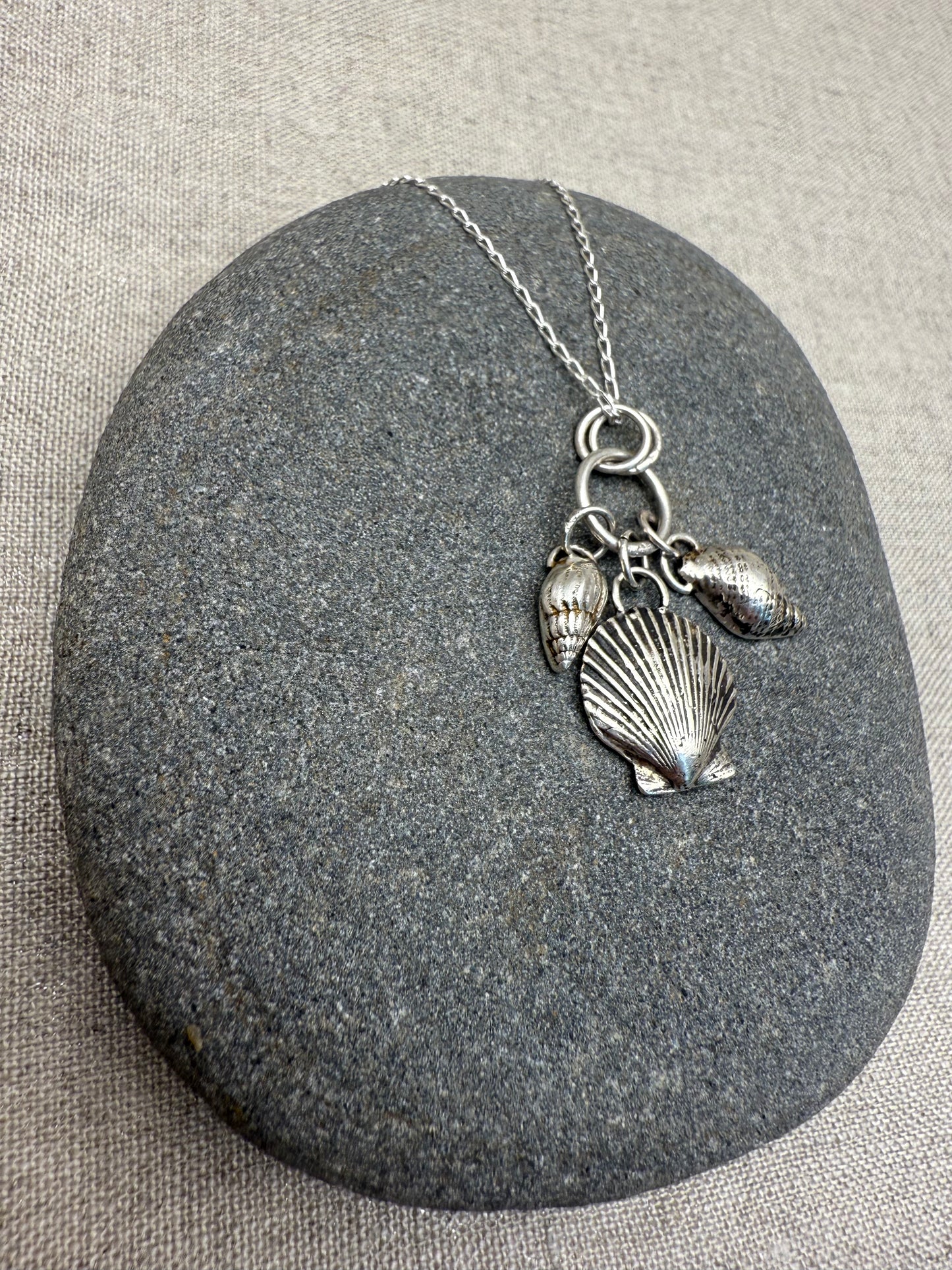 Silver necklace with shell pendants on a gray stone