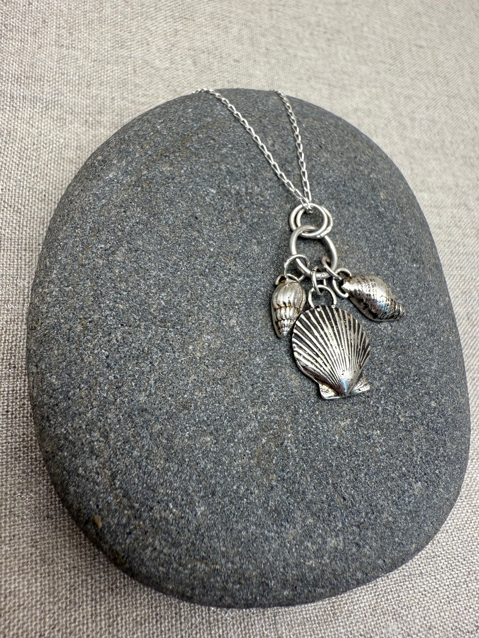 Silver necklace with shell pendants on a gray stone