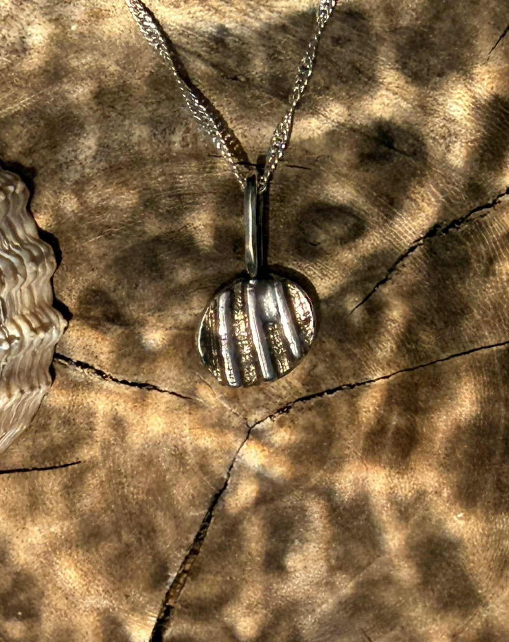 Silver necklace with a hand-shaped pendant on a textured brown surface