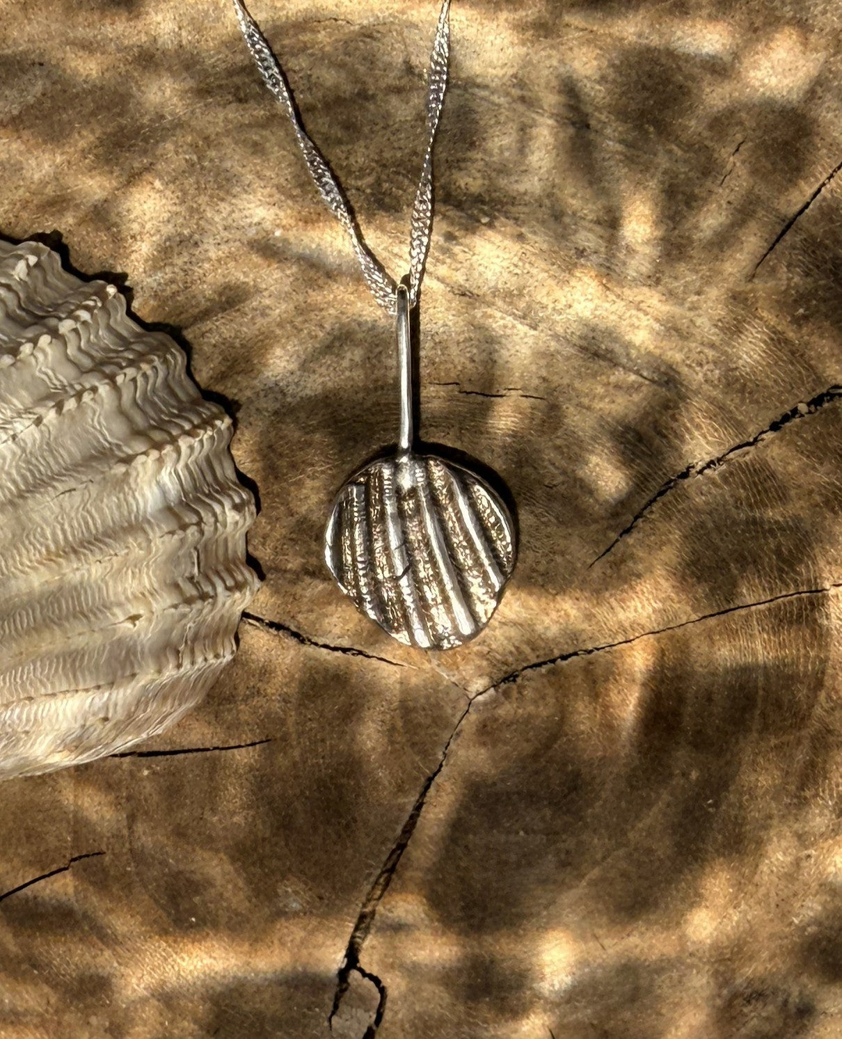 Silver necklace with a pendant on a textured brown surface
