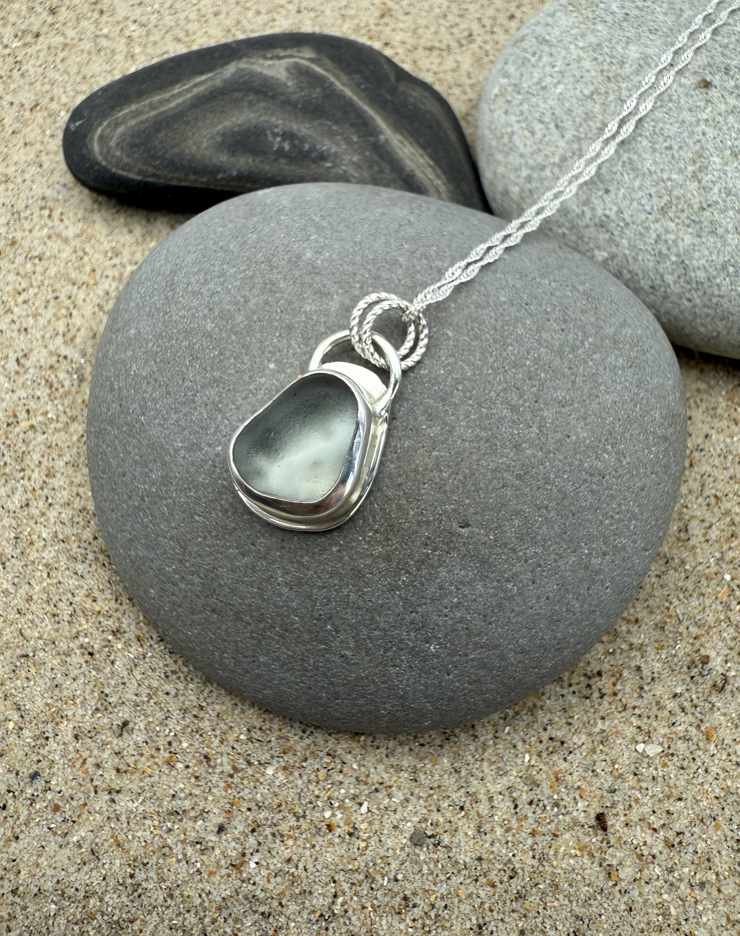Silver sea glass necklace with a pendant on a grey stone