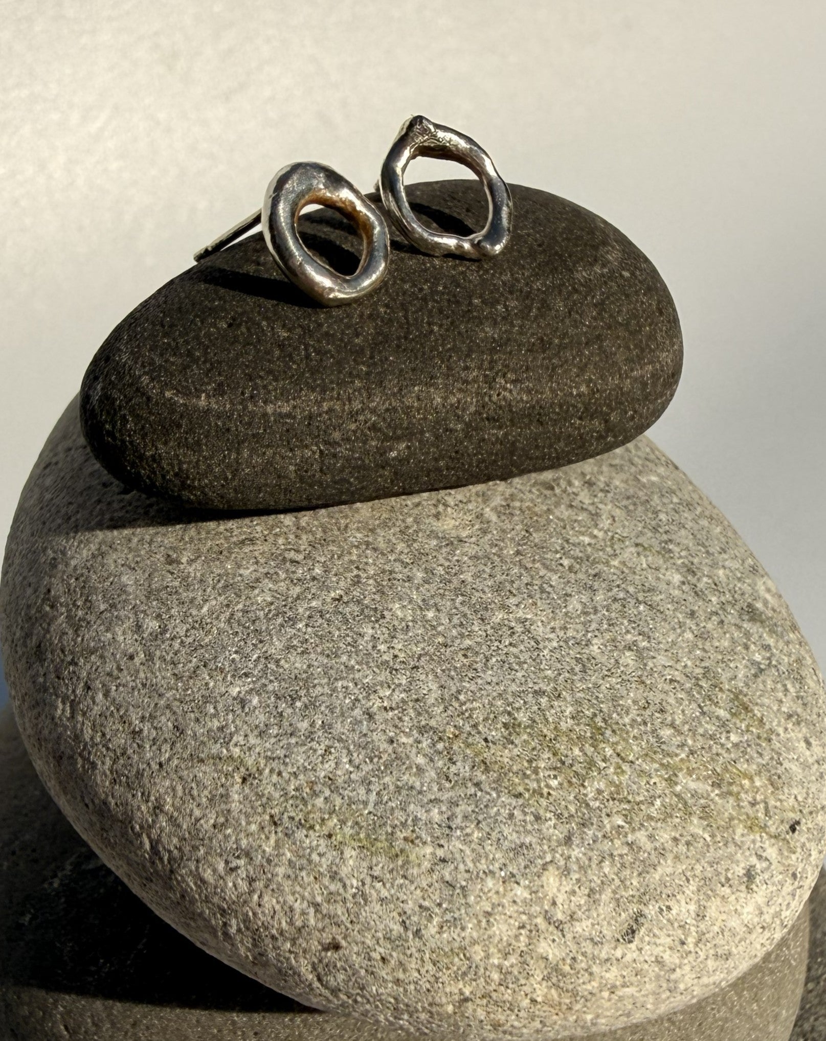 Silver earrings on a stack of stones