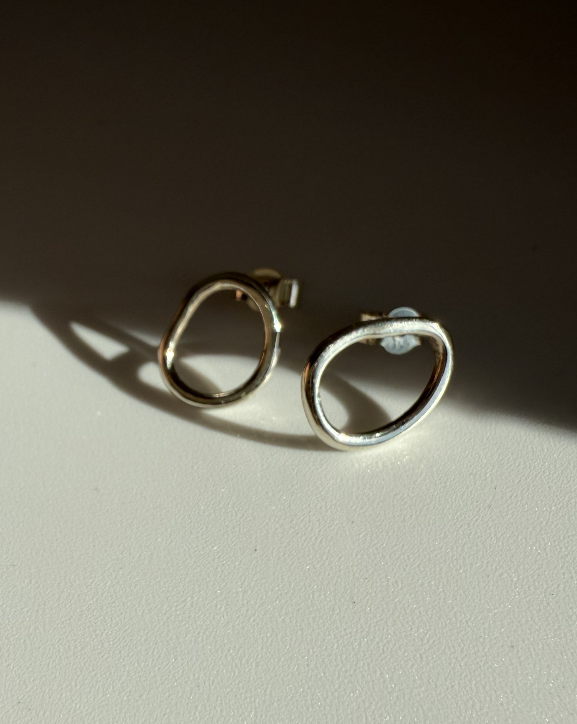 Pair of silver hoop earrings on a light surface with a dark background