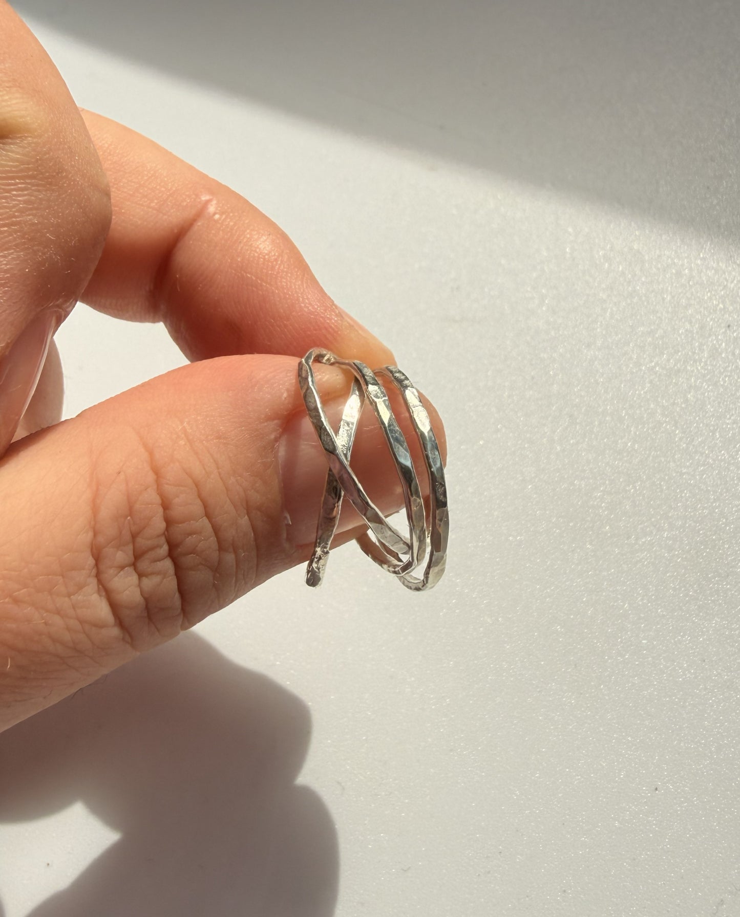 Silver ring on a finger against a light background