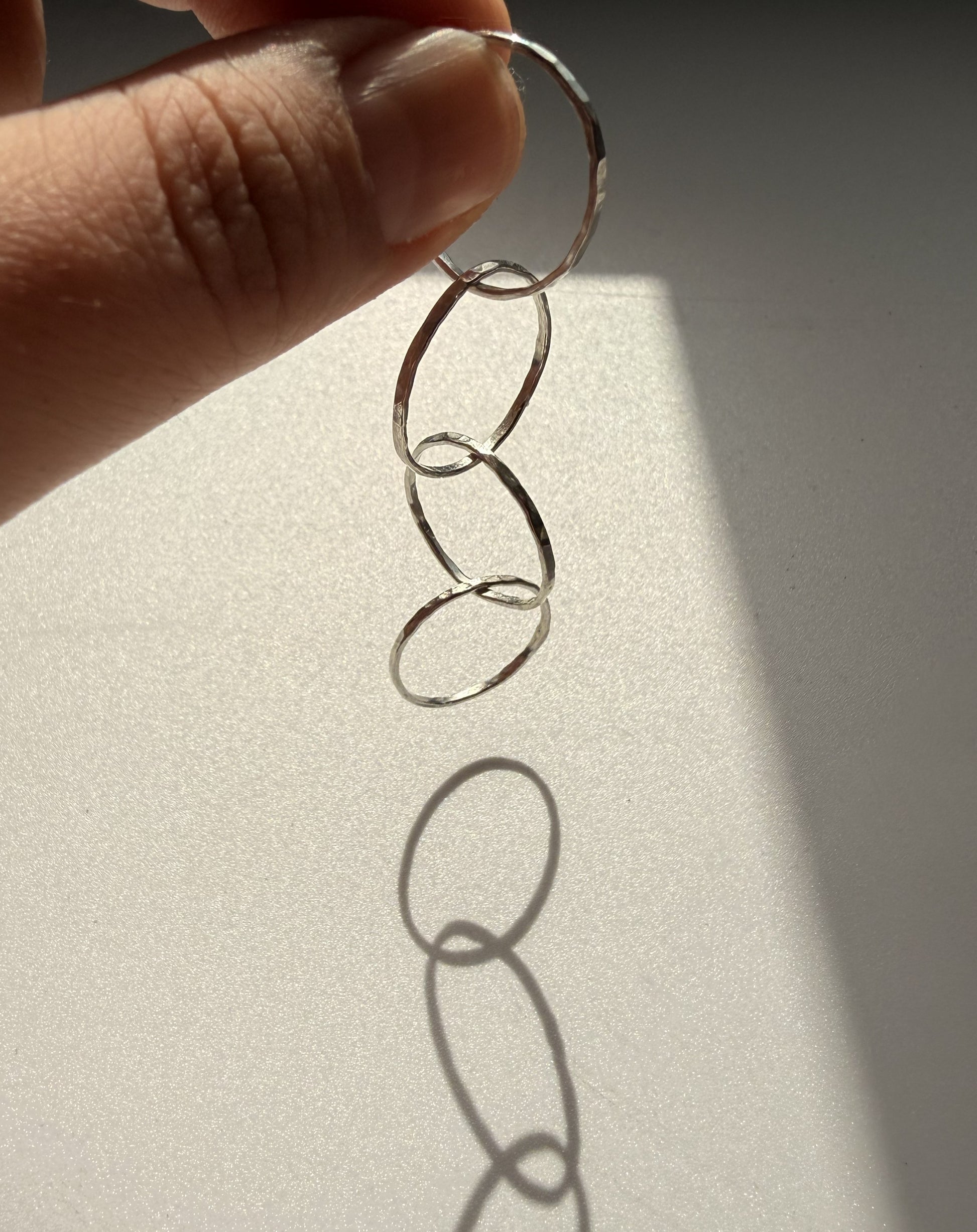 Silver interlinking rings held by a hand on a light background