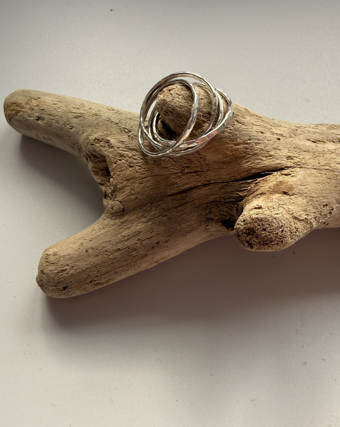 Silver ring on a piece of driftwood against a plain background