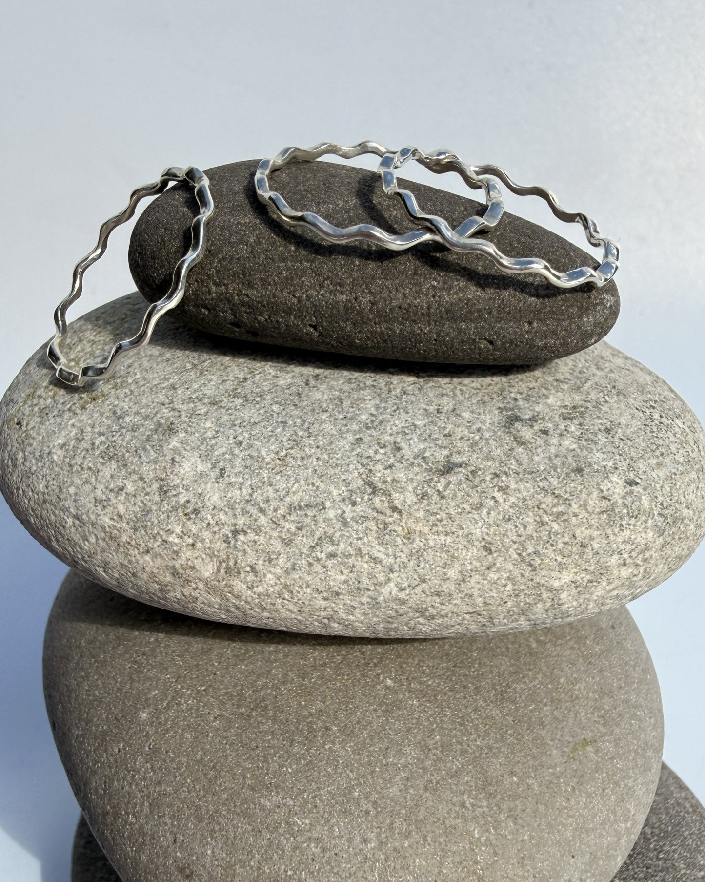 Stack of stones with a silver ring on top against a light gray background