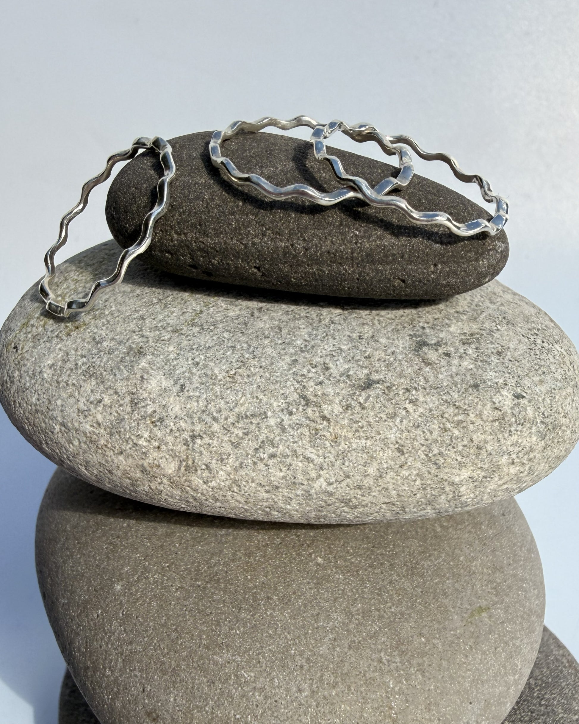 Stack of stones with a silver ring on top against a light gray background