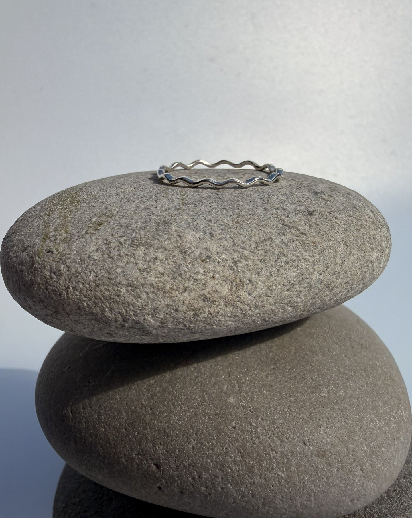 Silver ring on a stack of two stones with a light grey background