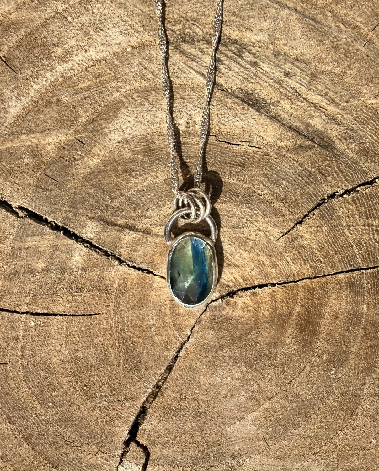 Necklace with a blue kyanite pendant on a wooden surface