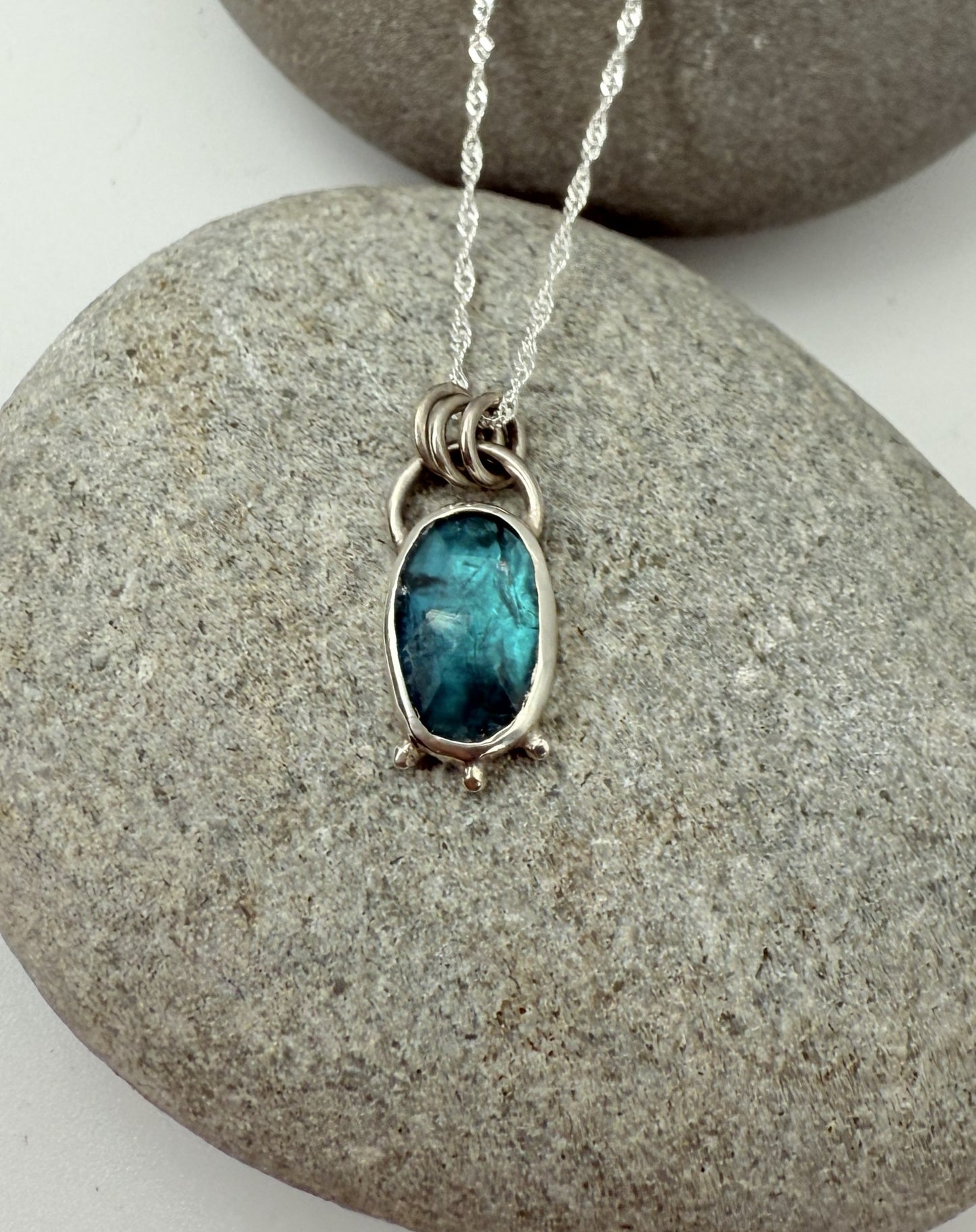 Necklace with a blue kyanite pendant on a stone surface