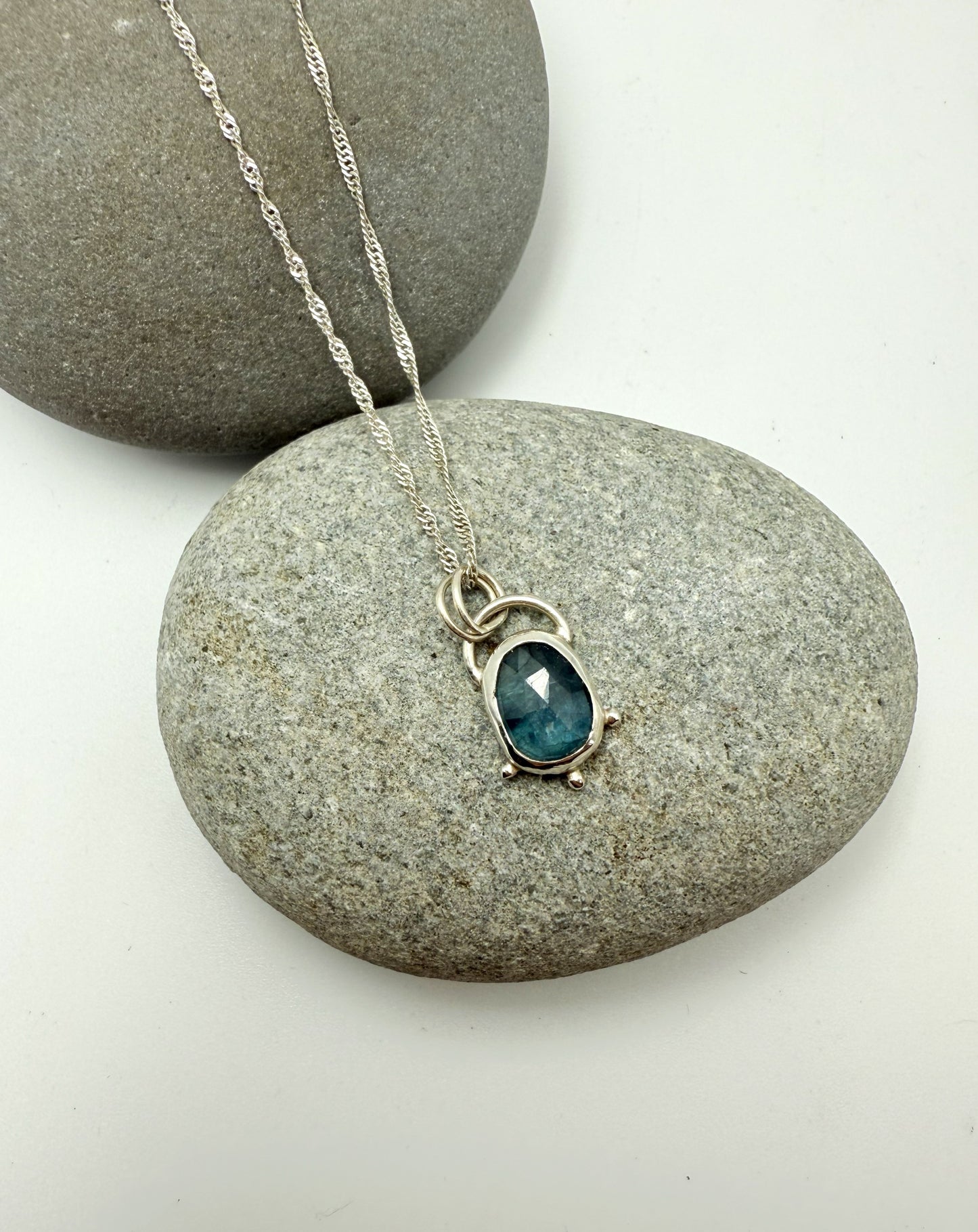 Necklace with a blue kyanite pendant on a stone surface