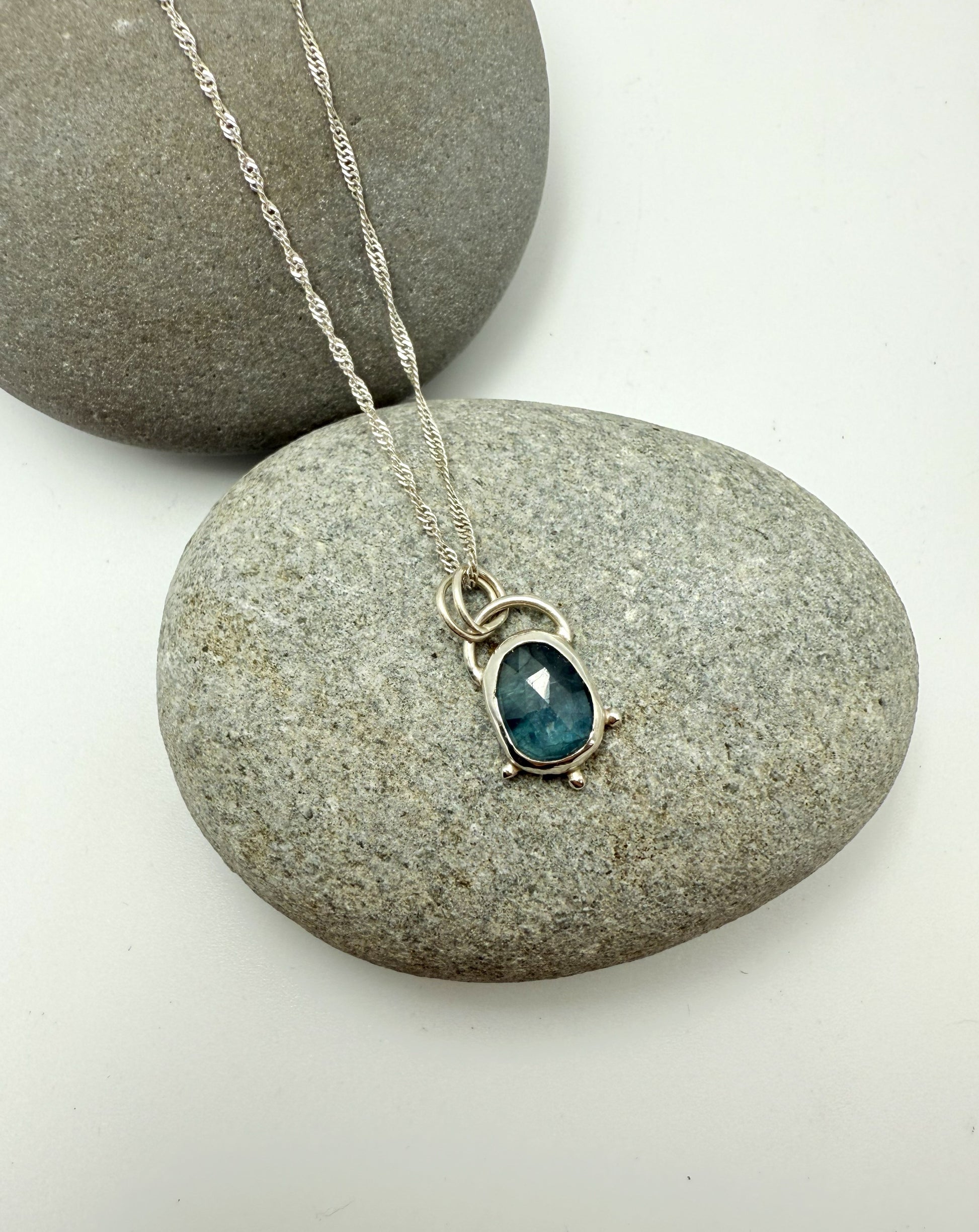 Necklace with a blue kyanite pendant on a stone surface