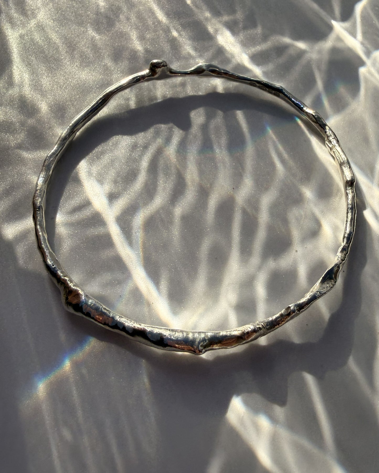 Silver bracelet on a textured white surface