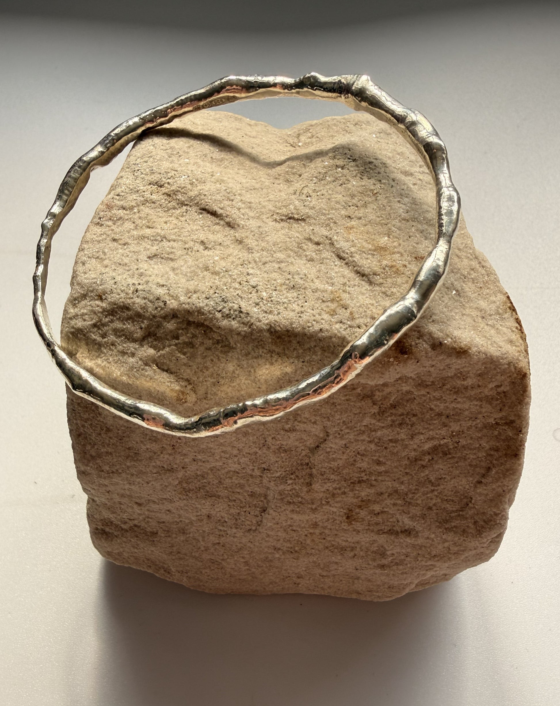 Silver bracelet on a textured beige stone